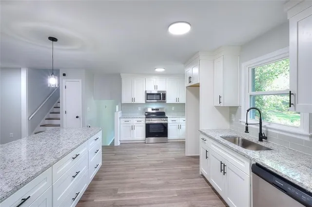 a large kitchen with granite countertop a large counter top a sink stainless steel appliances and windows