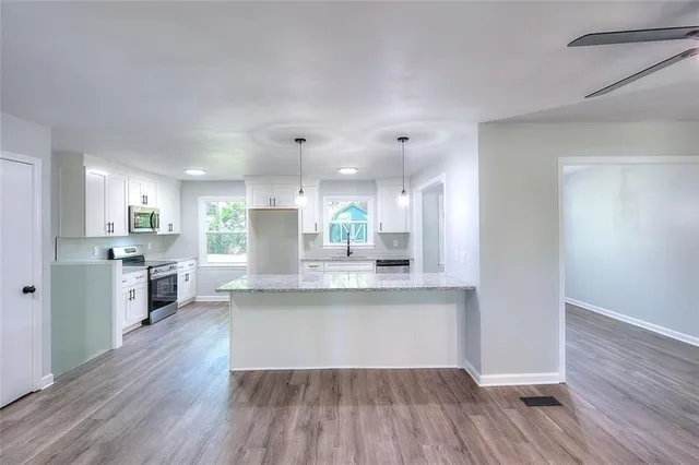 a large kitchen with cabinets wooden floor and stainless steel appliances