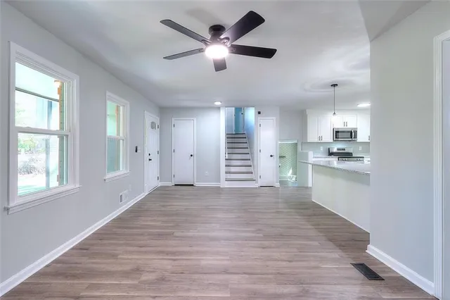 a view of an empty room with wooden floor and a window