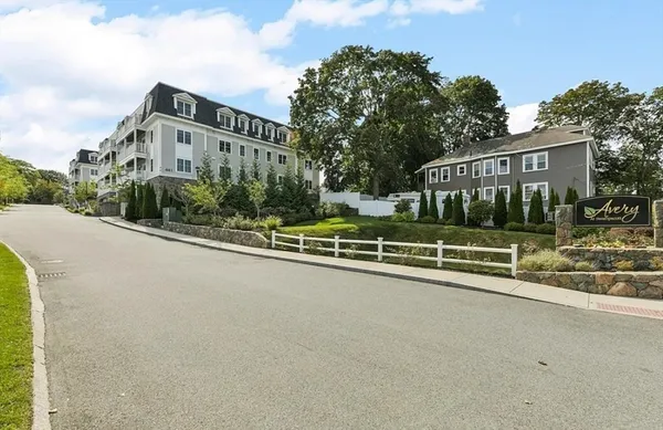a view of a house with a small yard and large trees