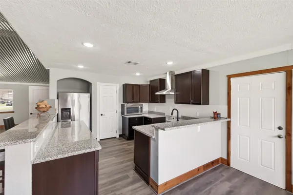a kitchen with stainless steel appliances kitchen island sink refrigerator and cabinets