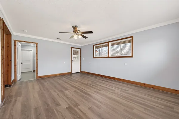 a view of an empty room with wooden floor and a window