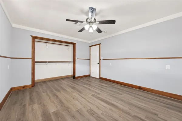 an empty room with wooden floor chandelier fan and windows