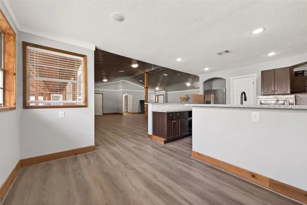 a large white kitchen with stainless steel appliances granite countertop a stove a sink dishwasher and a microwave oven with wooden floor