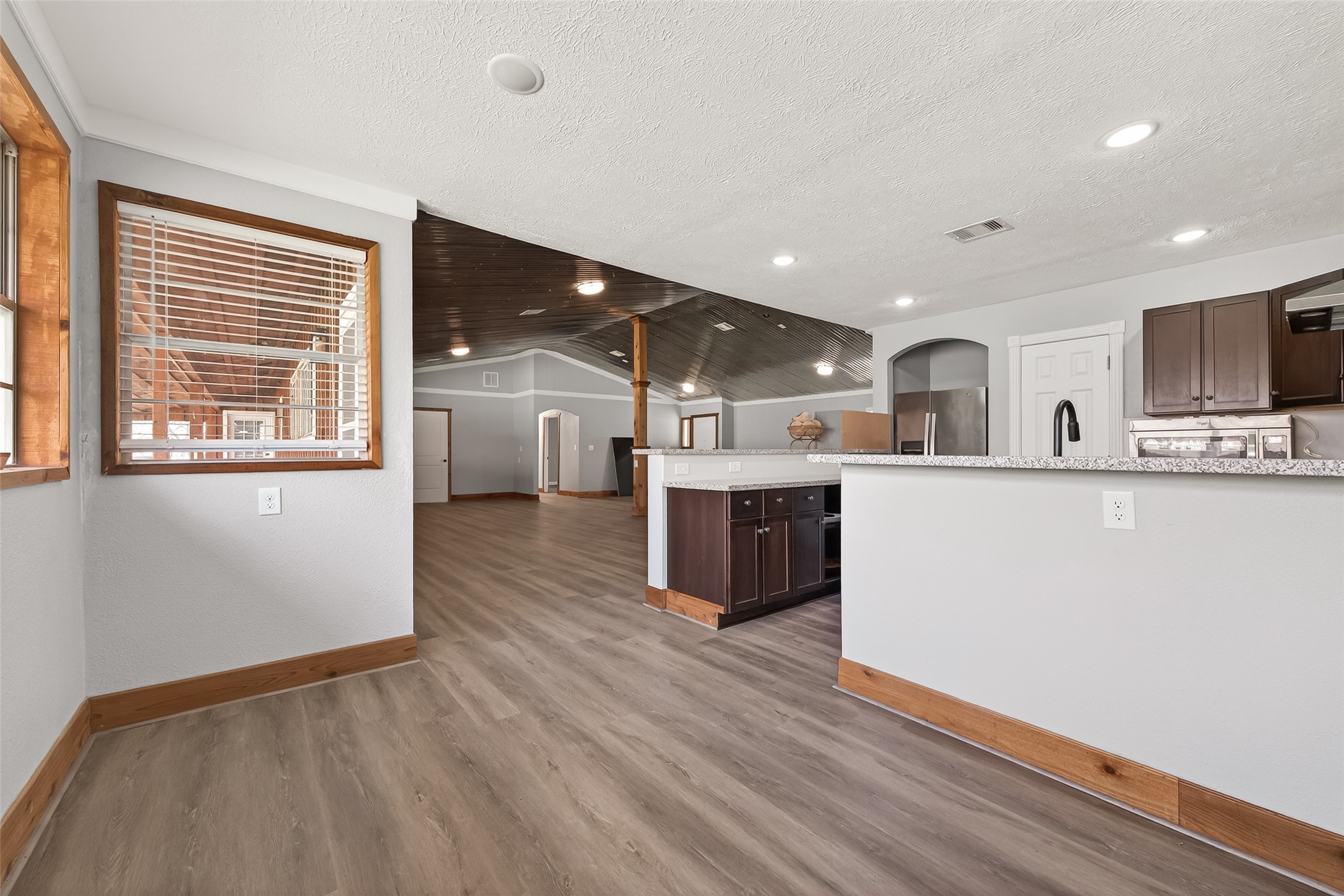 403 Wrangler Road Simonton, TX 77485 - Photo 21 of 33 a large white kitchen with stainless steel appliances granite countertop a stove a sink dishwasher and a microwave oven with wooden floor