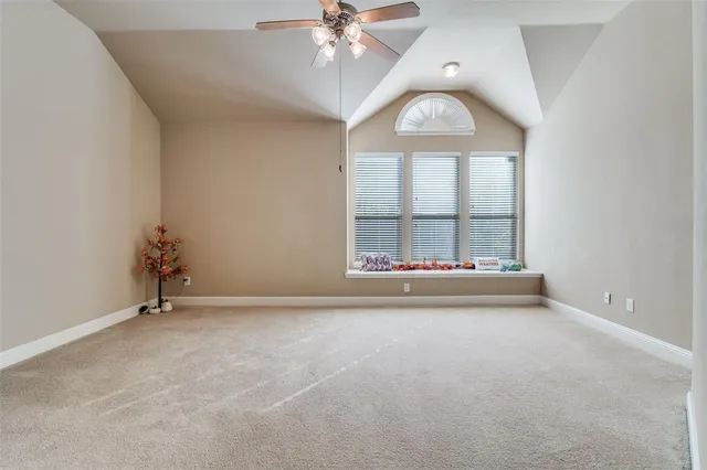 an empty room with chandelier fan and windows