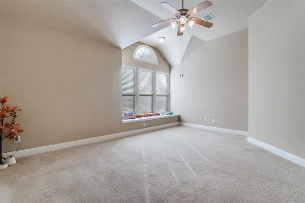 an empty room with chandelier fan and windows
