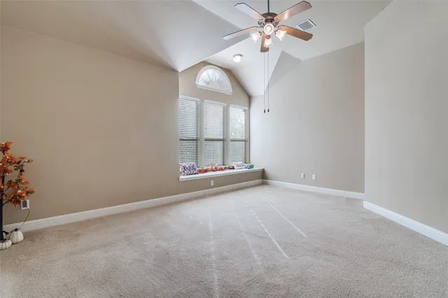 an empty room with chandelier fan and windows