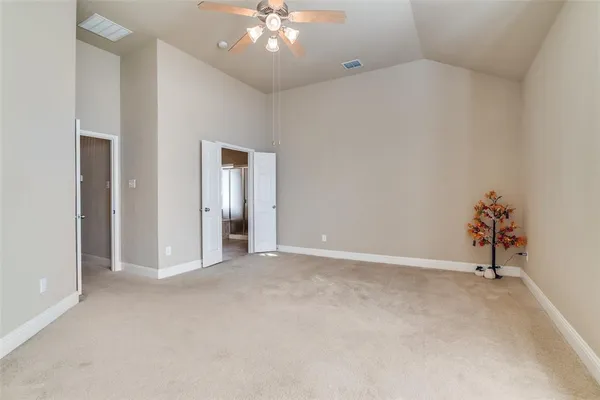 a view of an empty room with a chandelier fan