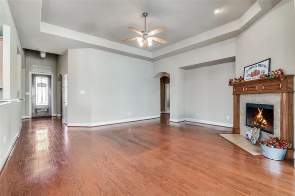 a view of an empty room with wooden floor fireplace and a window