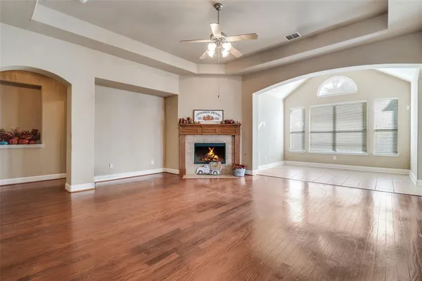 an empty room with wooden floor fireplace and windows