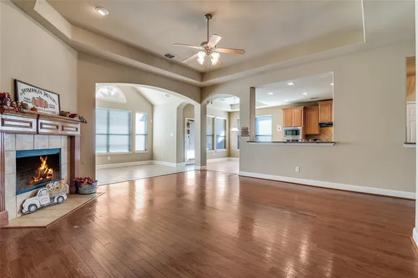 a view of a livingroom with a fireplace a ceiling fan and windows