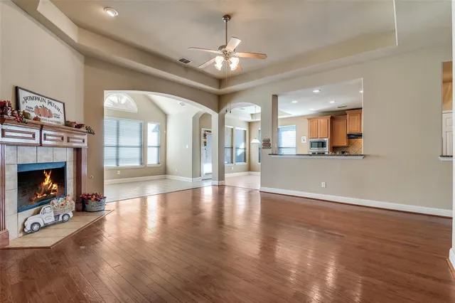 a view of a livingroom with a fireplace a ceiling fan and windows