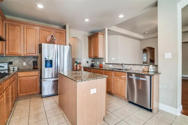 a kitchen with stainless steel appliances granite countertop a refrigerator and a stove top oven