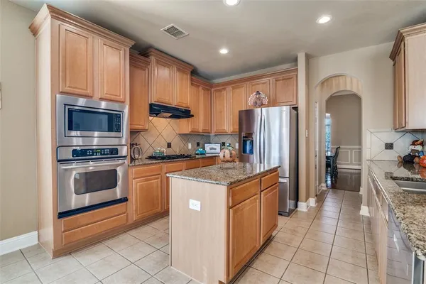 a kitchen with stainless steel appliances granite countertop a stove top oven a refrigerator a sink and dishwasher