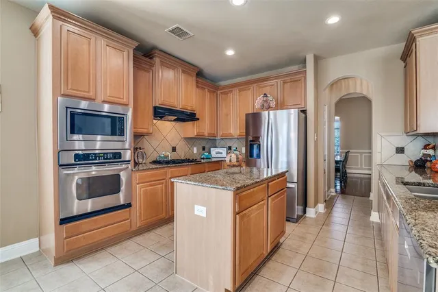 a kitchen with stainless steel appliances granite countertop a stove top oven a refrigerator a sink and dishwasher