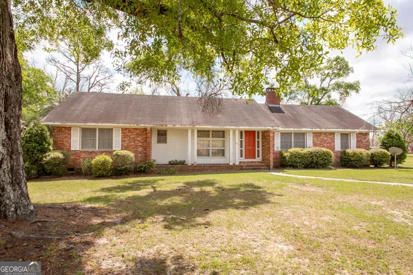 a front view of a house with a garden and trees