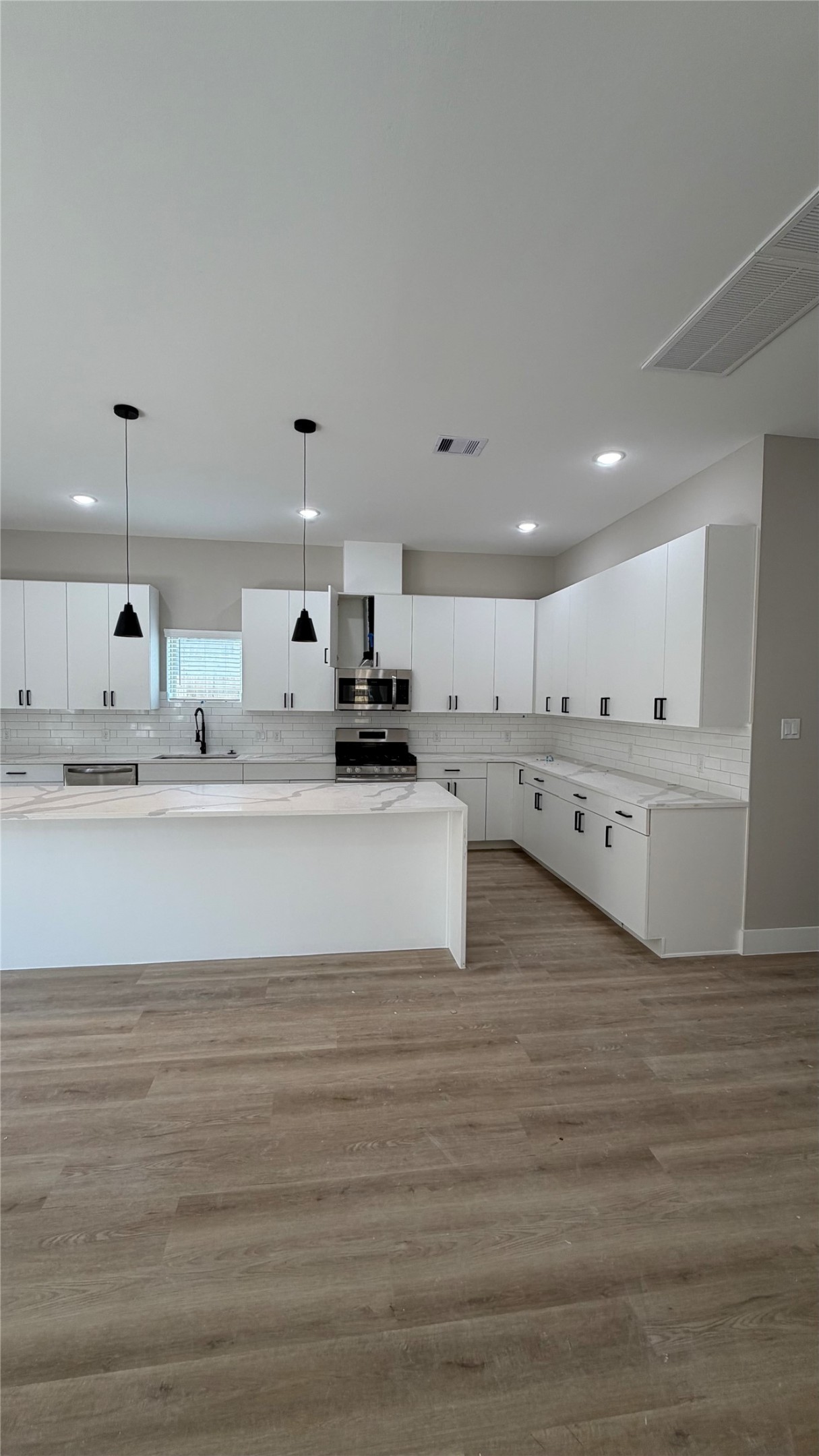 2607 Piemonte Avenue Cir Spring Spring, TX 77388 - Photo 7 of 38 a large white kitchen with kitchen island a stove a sink and white cabinets