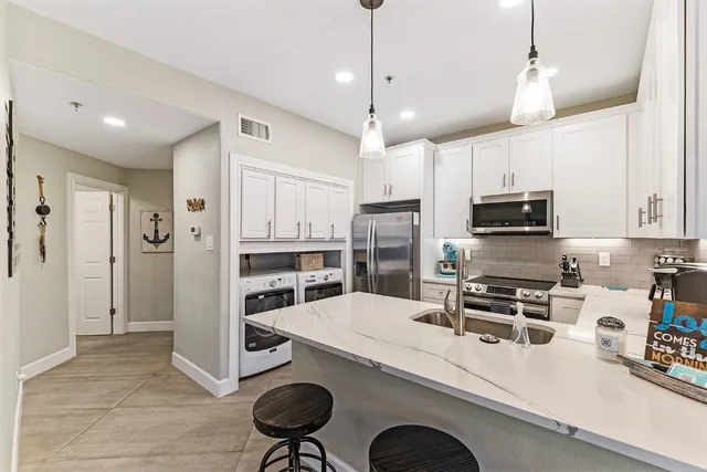 a kitchen with stainless steel appliances a refrigerator a stove a sink and chairs