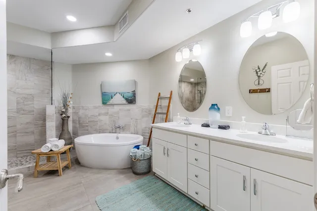 a spacious bathroom with a double vanity sink mirror and bathtub