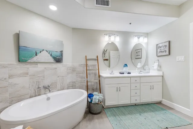 a bathroom with a double vanity sink mirror and bathtub