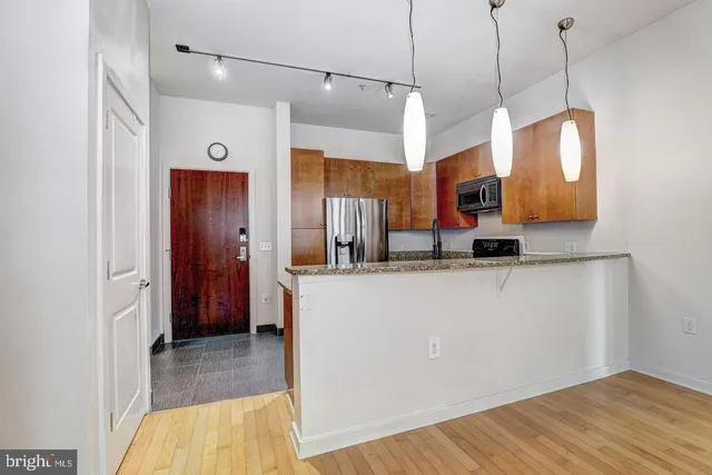 a kitchen view with stainless steel appliances a refrigerator and a wooden floor