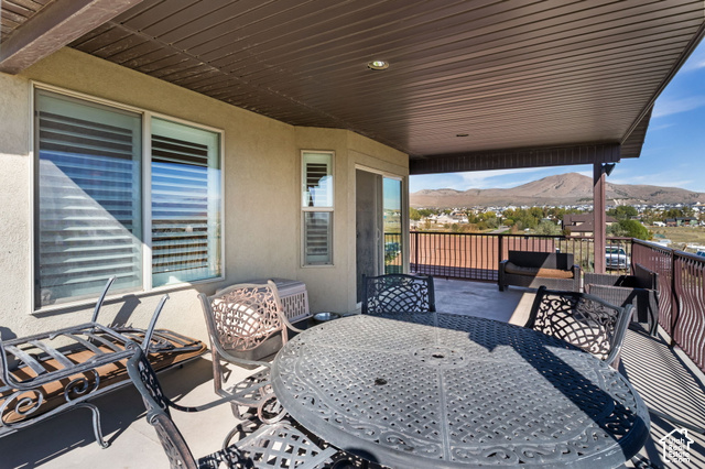 9044 North Cedar Pass Road Eagle Mountain, UT 84005 - Photo 44 of 63 Covered outdoor patio with a mountain backdrop, featuring a dark brown slatted ceiling and recessed lighting