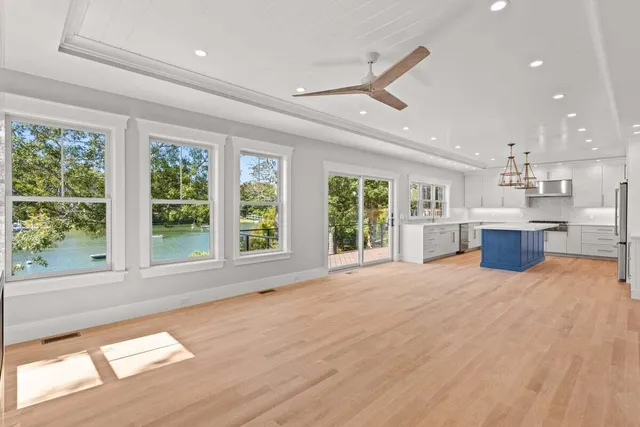 a view of an empty room with a window and kitchen view