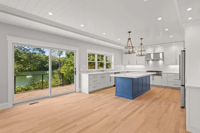 a large kitchen with a large counter top a sink stainless steel appliances and cabinets