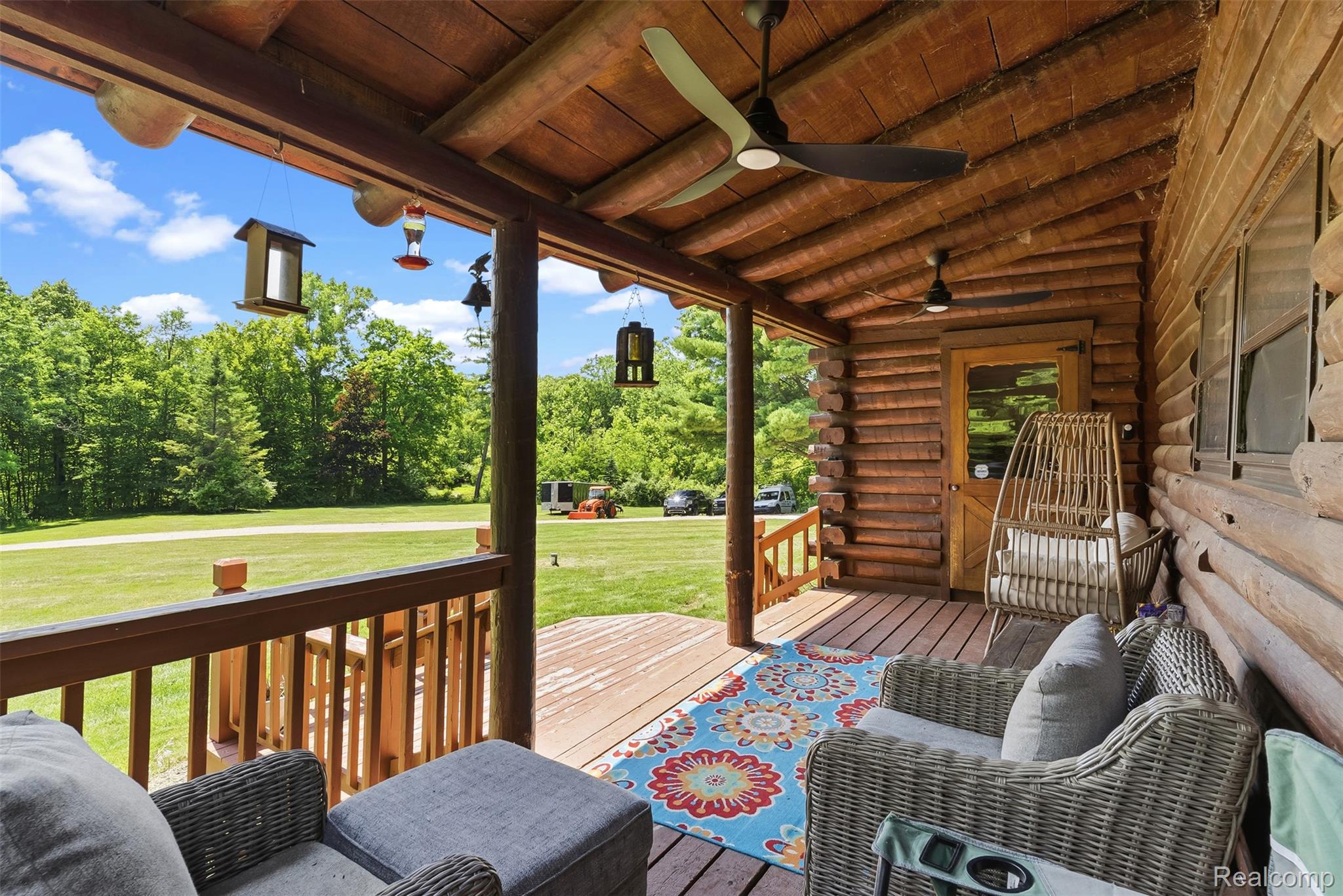 3656 Stanley Road Columbiaville, MI 48421 - Photo 44 of 65 Expansive wooden deck with log cabin siding and a tongue-and-groove wood ceiling, complemented by two ceiling fans