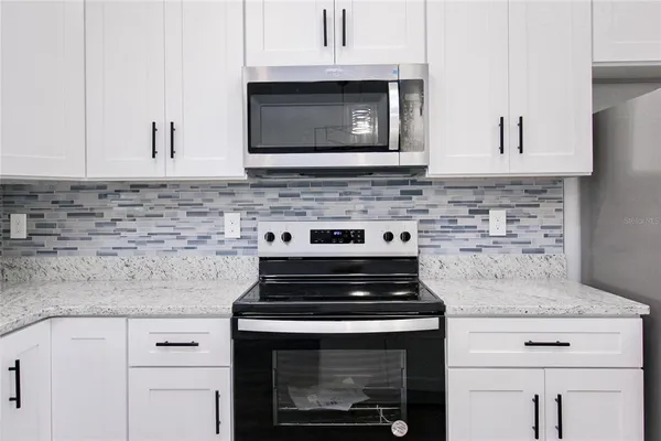 a kitchen with microwave cabinets and stove top oven