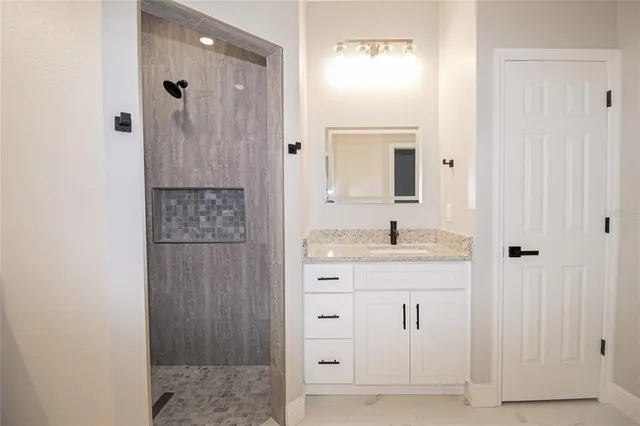 a bathroom with a granite countertop sink two mirror and shower