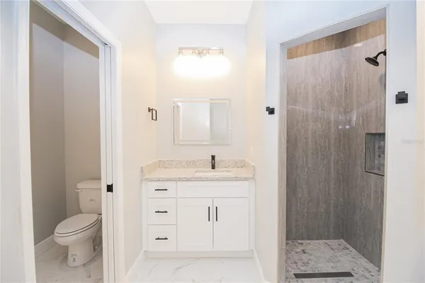 a bathroom with a granite countertop sink toilet and shower