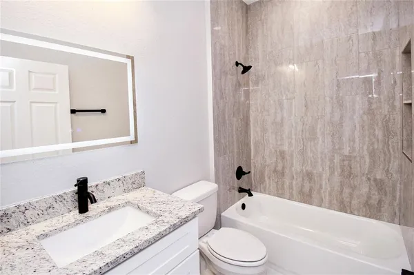 a bathroom with a granite countertop sink toilet and shower
