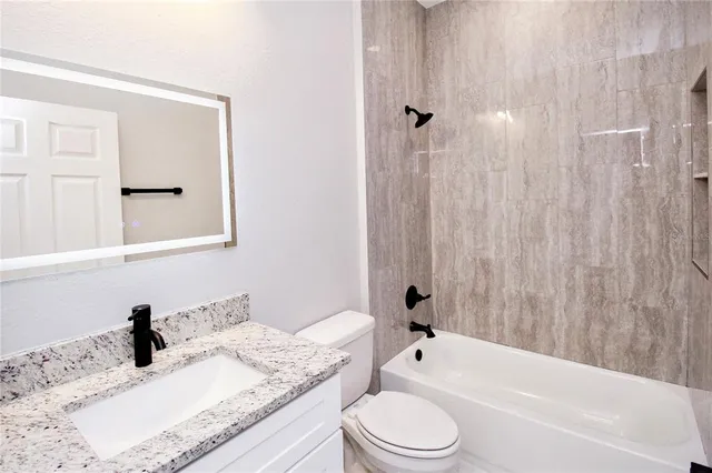 a bathroom with a granite countertop sink toilet and shower