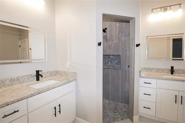 a bathroom with a granite countertop sink a mirror and shower