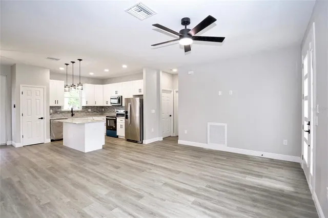 an open kitchen with a refrigerator and white cabinets