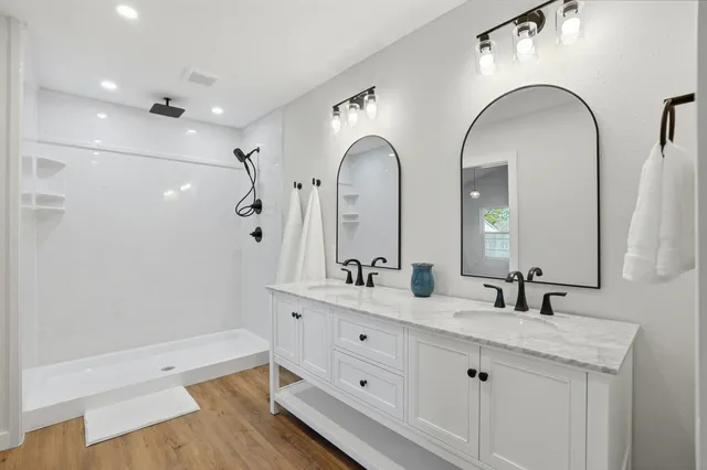 a spacious bathroom with a double vanity sink a mirror and a shower
