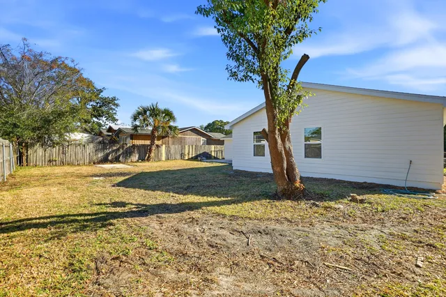 a tree in front of a house with a yard