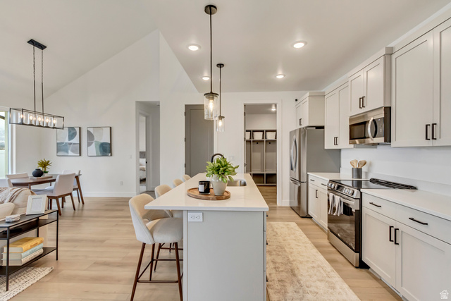 1389 1440 East, Unit 1 Payson, UT 84651 - Photo 2 of 17 Open-concept living space featuring a kitchen island with seating, stainless steel appliances, light wood-finish flooring, white cabinetry, and recessed lighting