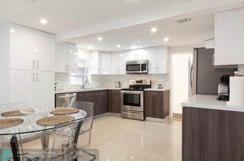 11450 Southwest 17th Street Davie, FL 33325 - Photo 13 of 56 a kitchen with stainless steel appliances kitchen island granite countertop a sink a stove a refrigerator a dining table and chairs