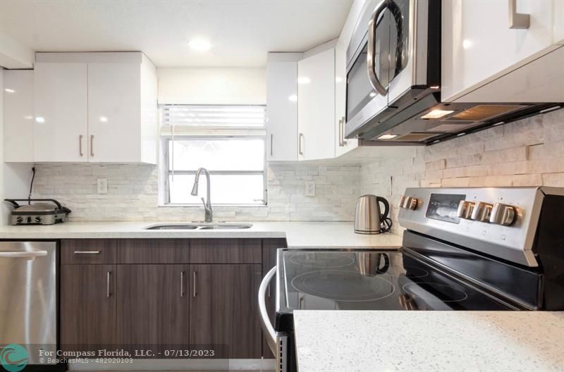 11450 Southwest 17th Street Davie, FL 33325 - Photo 18 of 56 a kitchen with stainless steel appliances granite countertop a sink stove and cabinets