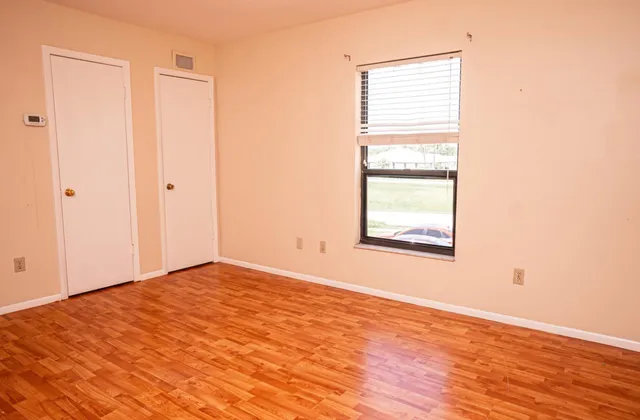 a view of an empty room with wooden floor and a window