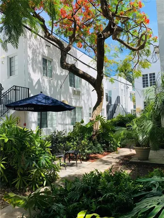 a view of a yard with plants and a table under an umbrella
