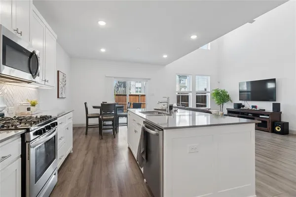 a kitchen with stainless steel appliances a stove top oven a sink a counter space and cabinets