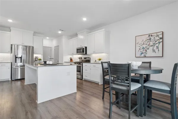 a kitchen with a table chairs refrigerator and microwave