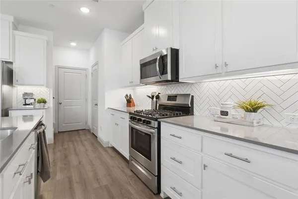 a kitchen with stainless steel appliances white cabinets and a stove top oven