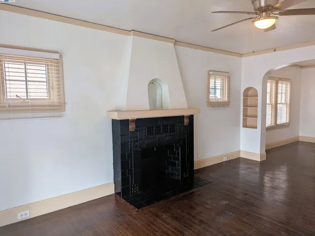 an empty room with wooden floor a fireplace and windows