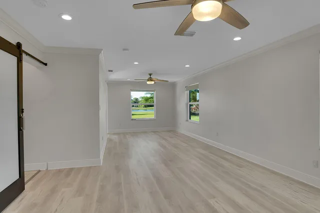 an empty room with wooden floor and windows