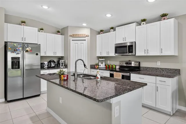 a kitchen with stainless steel appliances granite countertop a sink stove microwave and refrigerator